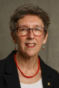 A person wearing a red necklace and black jacket Description automatically generated